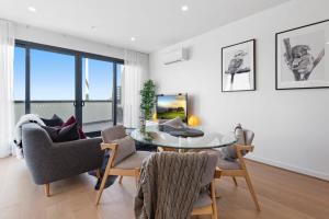 a living room with a glass table and chairs at Stylish and Convenient Two Bedroom Apartment in Burwood
