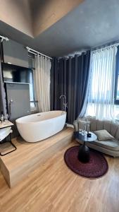 een grote badkamer met een groot bad en een bank bij AroRy Hotel in Da Lat