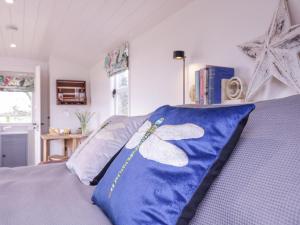 a bed with a blue pillow with a butterfly on it at Bumble's Retreat in Whepstead