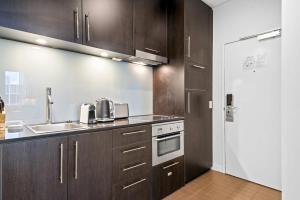cocina con armarios marrones, fregadero y nevera en Charming 1-Bed Central Studio Apartment en Melbourne