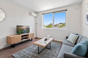 - un salon avec un canapé et une télévision dans l'établissement Polished 1-Bed St Kilda Pad in Prime Location, à Melbourne