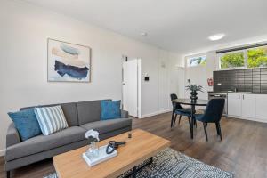 ein Wohnzimmer mit einem Sofa und einem Tisch in der Unterkunft Polished 1-Bed St Kilda Pad in Prime Location in Melbourne