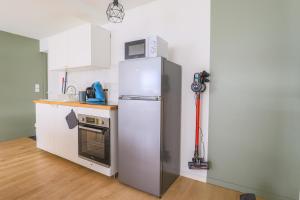 a kitchen with a refrigerator and a microwave at Appartement Familial - Avec Parking Privé Gratuit in Arras