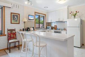 une cuisine avec un comptoir blanc et des tabourets dans l'établissement Spacious 2-Bed Apartment Minutes From Elwood Beach, à Melbourne