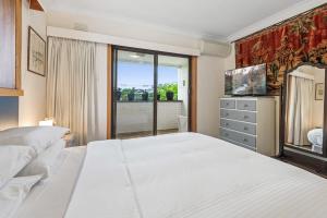 Un dormitorio con una gran cama blanca y una ventana en Spacious 2-Bed Apartment Minutes From Elwood Beach, en Melbourne