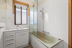 La salle de bains est pourvue d'une baignoire, d'un lavabo et d'une douche. dans l'établissement Spacious 2-Bed Apartment Minutes From Elwood Beach, à Melbourne