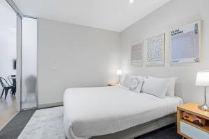 a white bedroom with a white bed and a table at Sophisticated CBD 2-Bed Apartment by Yarra River in Melbourne
