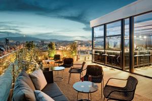 a rooftop patio with a couch and tables and chairs at NH Collection Barcelona Gran Hotel Calderon in Barcelona