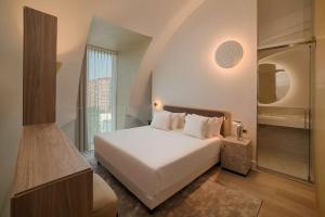 a bedroom with a white bed and a walk in shower at NH Collection Milano CityLife in Milan