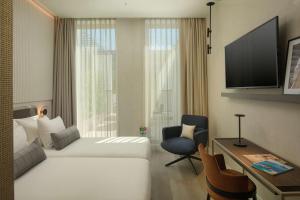 una camera d'albergo con letto, scrivania e TV di NH Collection Milano CityLife a Milano