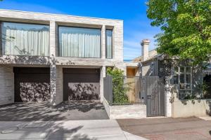 een huis met twee garagedeuren en een hek bij Impeccably Chic 3-Bed House by Fawkner Park in Melbourne