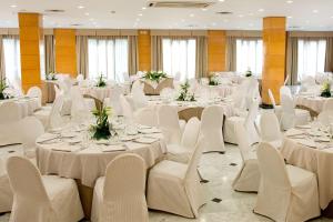 une salle de banquet avec des tables blanches et des chaises blanches dans l'établissement NH Ciutat de Reus, à Reus