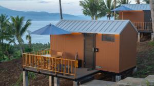 een klein huis met een paraplu en een terras bij Bobocabin Bunaken Hills, Manado in Manado