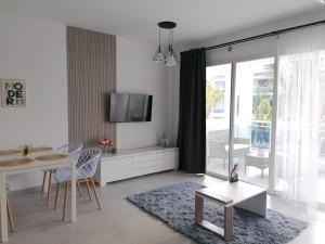 a white living room with a table and a tv at Star of Caribbean- Estrella Dominicus Bayahibe in Bayahibe