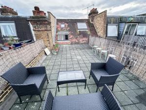 eine Terrasse mit 2 Stühlen, einem Tisch und einem Backsteingebäude in der Unterkunft Lovely 3 bedroom maisonette with private roof terrace in Hammersmith in London