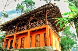 an orange house with a thatched roof at Camping situ cileunca in Palayangan