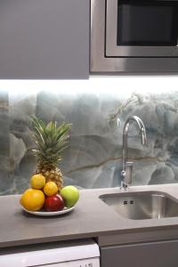 a plate of fruit on a counter next to a sink at Cosmo Apartments Consell de Cent - Plaza Universitat in Barcelona