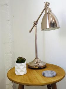 einem Tisch mit einer Lampe und einer Topfpflanze darauf in der Unterkunft Urban Warehouse in Queanbeyan