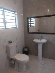 a white bathroom with a toilet and a sink at Kasuba Two Bedroom Apartment in Livingstone +12 photos