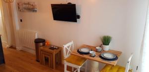 a small table with chairs and a television on the wall at Hill House Lodge in Stoke Gabriel