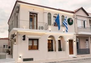una casa blanca con dos banderas delante en Aegli Suites en Levádeia