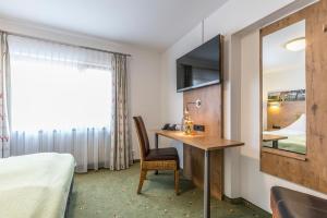 ein Hotelzimmer mit einem Schreibtisch und einem Bett in der Unterkunft Rührberger Hof Hotel & Restaurant Grenzach-Wyhlen bei Basel in Grenzach-Wyhlen