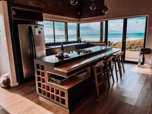 a kitchen with a counter and a refrigerator and some windows at Witsand Whalecliff accommodation in Witsand