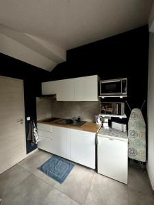 a kitchen with white cabinets and a microwave at Studio tout équipé aux pieds des Vosges in Leimbach