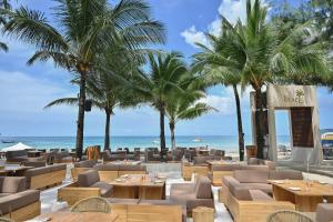 un restaurante con mesas y palmeras en la playa en Arinara Beach Resort Phuket - SHA Extra Plus, en Bang Tao Beach