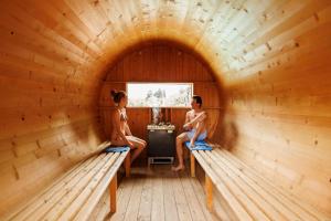 dos personas sentadas en bancos en una sauna en Camping Zoo, en Arco