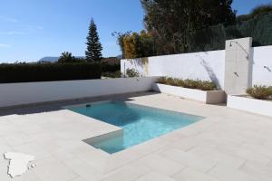 einen Pool in einem Garten mit einem weißen Zaun in der Unterkunft Casita Adelfa in Calpe
