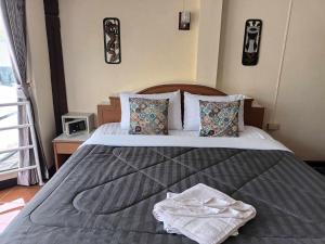 a bedroom with a large bed with towels on it at Patong Rose Guest House in Patong Beach