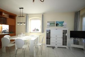 - une salle à manger blanche avec une table et des chaises blanches dans l'établissement Haus am Fuchskamp, à Grömitz