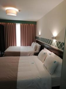 a hotel room with two beds and a window at Hotel Primavera in Amadora