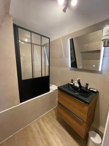 La salle de bains est pourvue d'un lavabo noir et d'un miroir. dans l'établissement Hôtel De La Mer - Deauville Blonville - Boutique Hôtel de charme vue Mer ou Campagne - Accès direct plage, à Blonville-sur-Mer