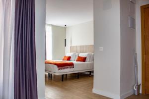 1 dormitorio con cama blanca y almohadas de color naranja en Apartamentos Tudanca Miranda, en Miranda de Ebro