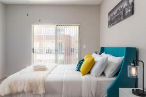 a bedroom with a white bed with colorful pillows at Corporate Housing by MGM in Farmers Branch