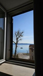 - une fenêtre avec vue sur un arbre et l'océan dans l'établissement Apartments Magli, à Kaštela