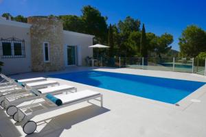 a swimming pool with lounge chairs next to a house at Villa Dream - Santa Eulalia in Cala Llonga