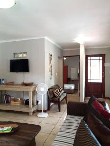 ein Wohnzimmer mit einem Sofa und einem TV in der Unterkunft Gecko Cottages in Hectorspruit