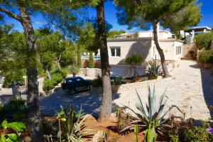 a car parked in front of a house with trees at Villa Dream - Santa Eulalia in Cala Llonga