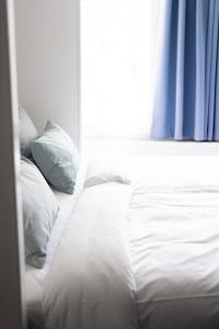 uma cama com lençóis brancos e almofadas ao lado de uma janela em Arnfeldt Hotel & Restaurant em Ærøskøbing