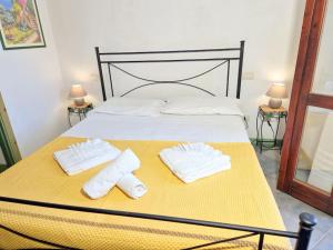 łóżko z dwoma białymi ręcznikami na żółtym kocu w obiekcie La Terrazza w mieście Villasimius