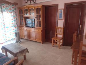 a living room with a tv and a wooden cabinet at Pueblo de sensaciones. in Chipiona