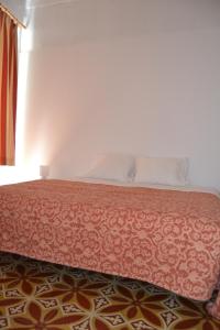 a bedroom with a bed with a red bedspread and a window at Casa Almirante Reis in Olhão