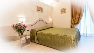 a hotel room with a bed and a vase of flowers at Hotel Gialletti in Orvieto