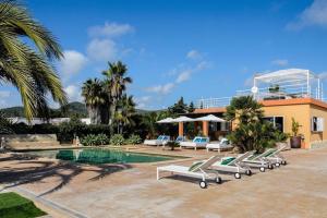 a resort with a pool with lounge chairs and a building at Villa Marissa - Ibiza in Sant Francesc de s'Estany
