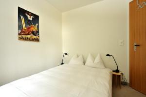 a bedroom with a white bed with a poster on the wall at Chesa Igna in Arosa