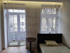 1 dormitorio con cama, mesa y ventanas en Kambarys su balkonu ir didele lova Kauno centre #6 en Kaunas