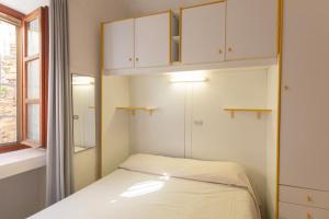 a small bedroom with white cabinets and a bed at Appartamento al Cotone - HelloElba in Marciana Marina